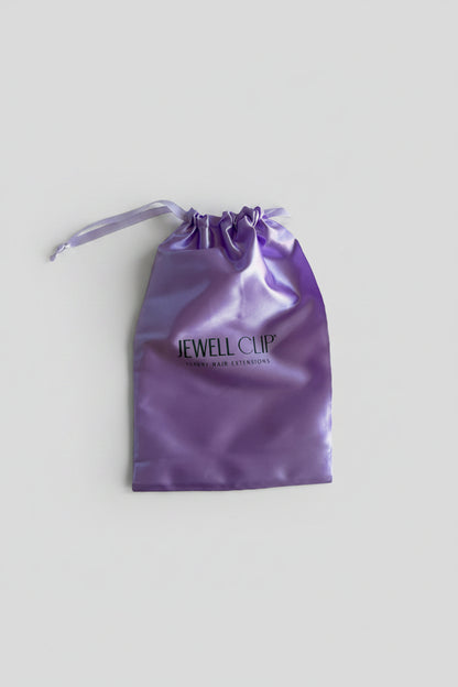 Purple drawstring bag with 'Jewell Clip' branding on a light wooden surface